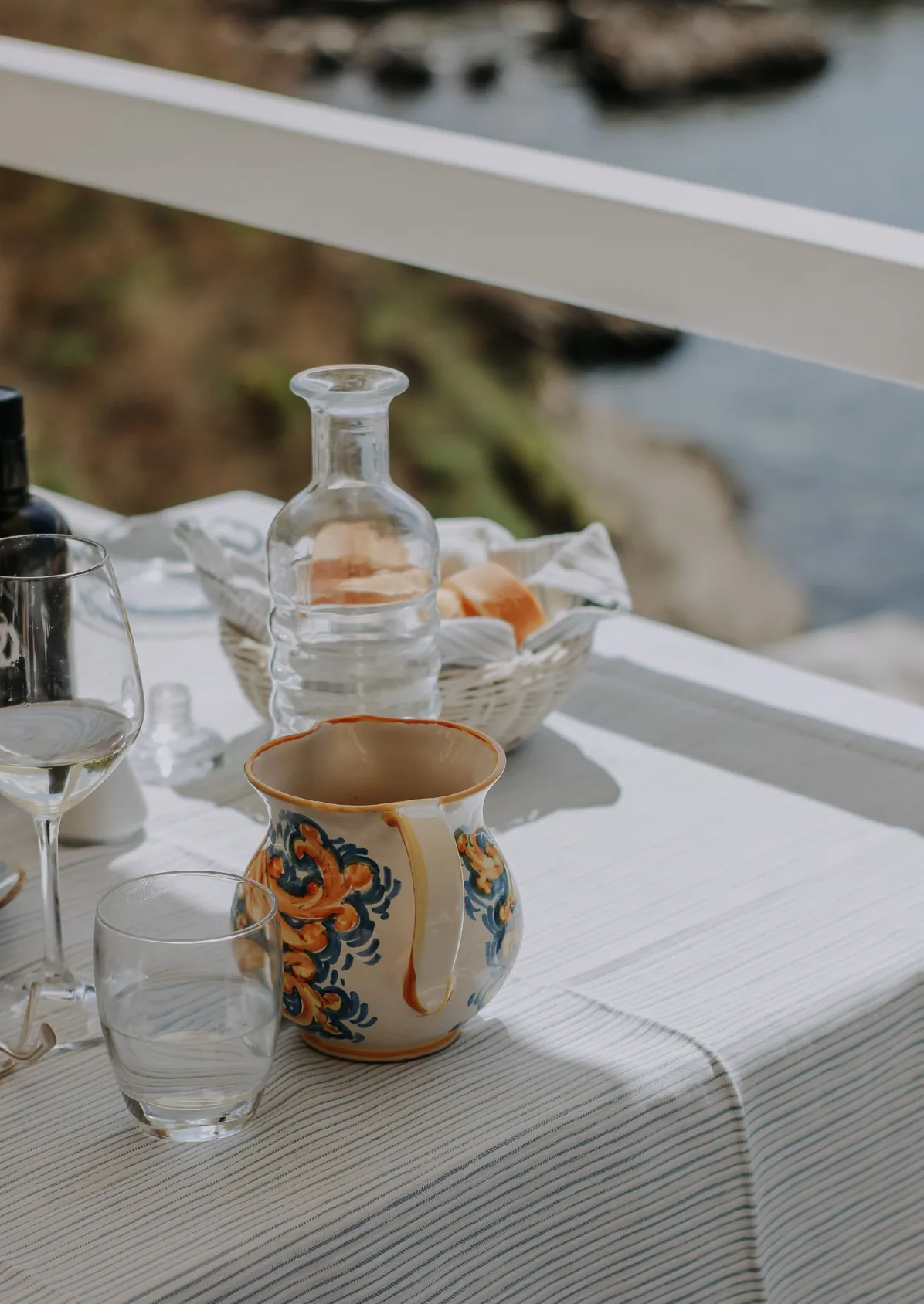 Tavola apparecchiata con brocca in ceramica e vista sul mare
